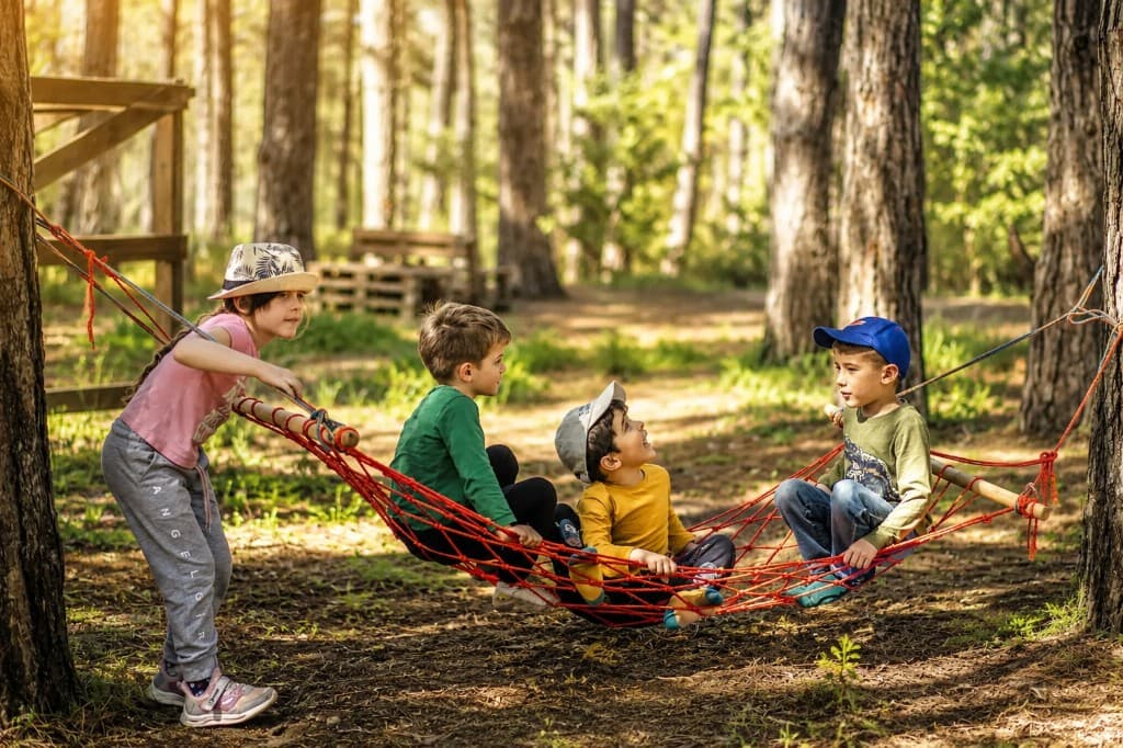 Children playing together on an outdoor rope hammock during a nature-based OT group